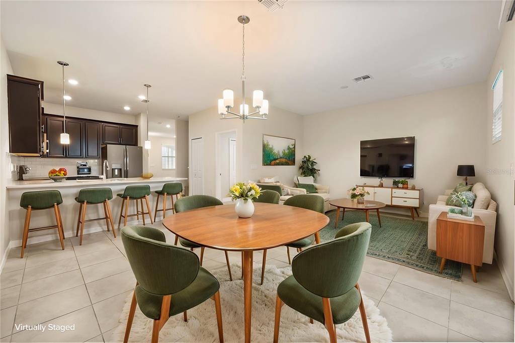 A dining area with a round table and green chairs opens to a kitchen and living room — 4642 TRIBUTE TRAIL, KISSIMMEE, FL