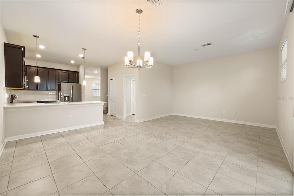 An open-concept kitchen with dark cabinets and a dining area with tile flooring — 4642 TRIBUTE TRAIL, KISSIMMEE, FL