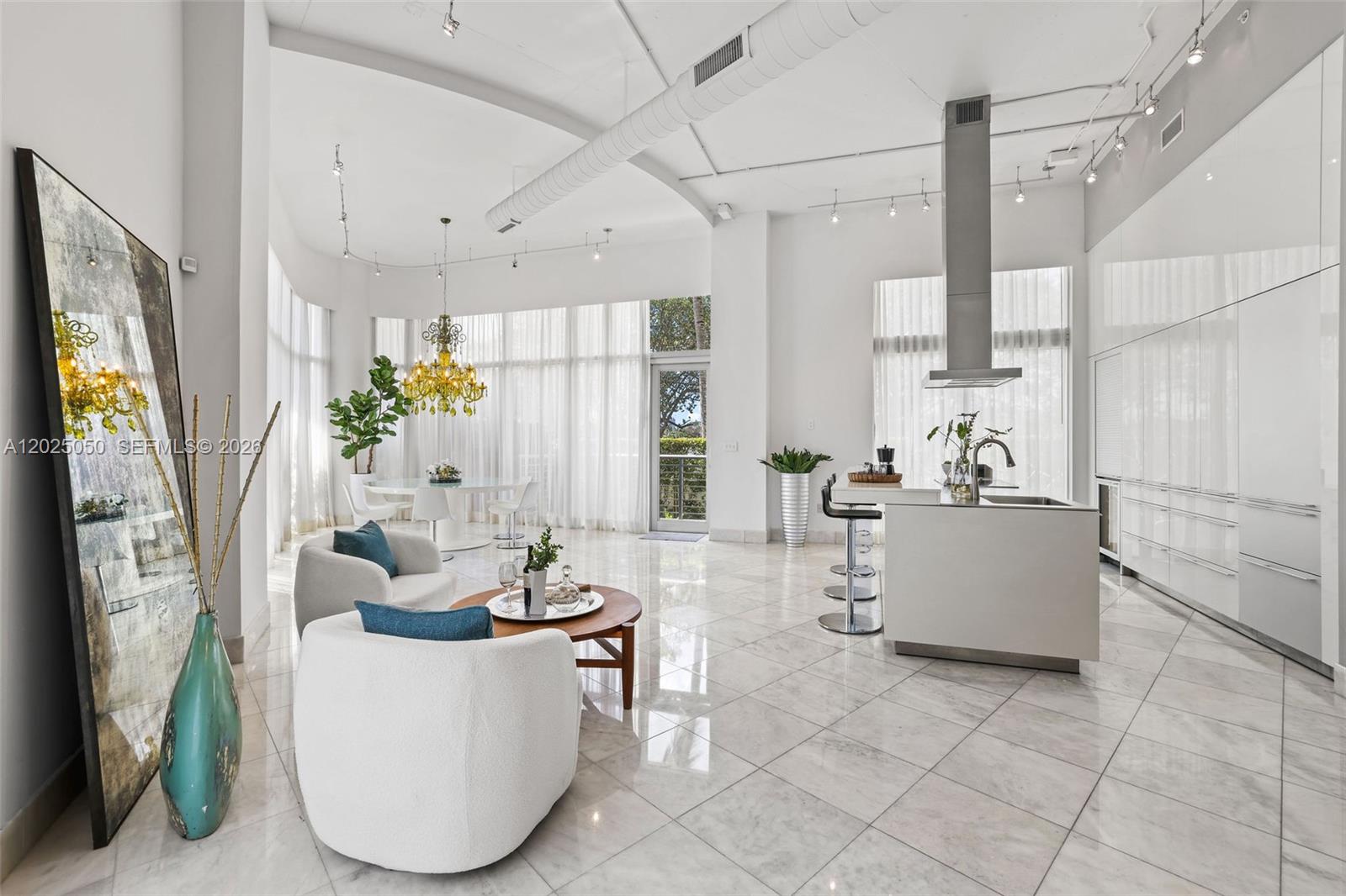 An open-concept living and dining area features white tile floors, high ceilings, and modern cabinetry — 2001 Meridian Ave # 101, Miami Beach FL 33139, MIAMI BEACH, FL