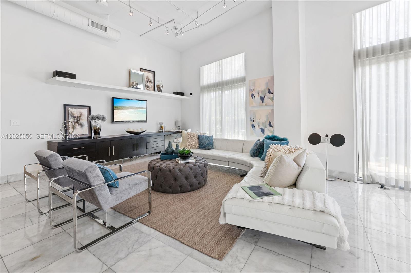 A modern living room features a white sectional sofa, gray armchairs, and marble flooring — 2001 Meridian Ave # 101, Miami Beach FL 33139, MIAMI BEACH, FL