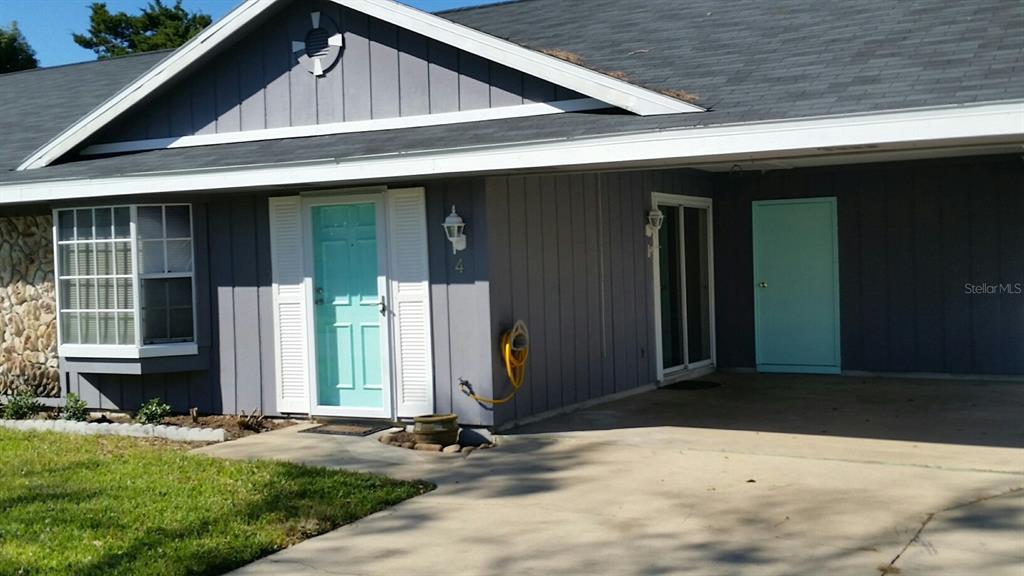 A gray house exterior features a light blue front door, a carport, and stone siding — 4 PAR DRIVE, NEW SMYRNA BEACH, FL