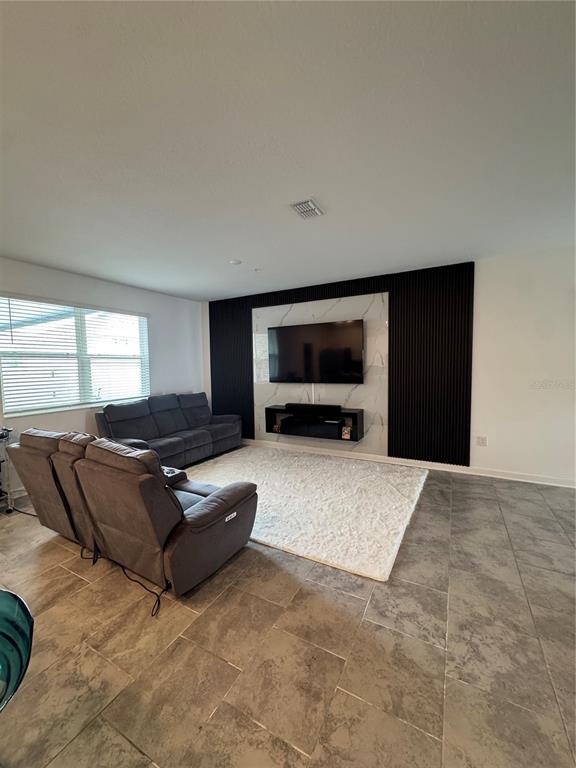 A living room features a grey sofa, a recliner, and a wall-mounted television on marble — 11924 BOLDFACE DRIVE, ORLANDO, FL