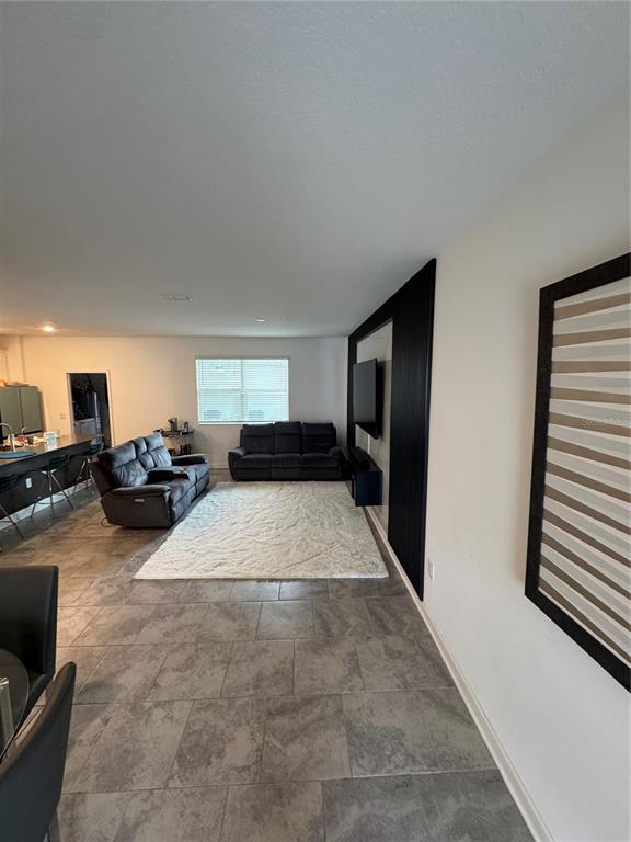 A living room features gray tile flooring, a white area rug, and a black accent wall — 11924 BOLDFACE DRIVE, ORLANDO, FL