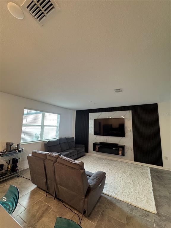 A living room features a gray sofa, a recliner, and a black-and-white marble accent wall — 11924 BOLDFACE DRIVE, ORLANDO, FL