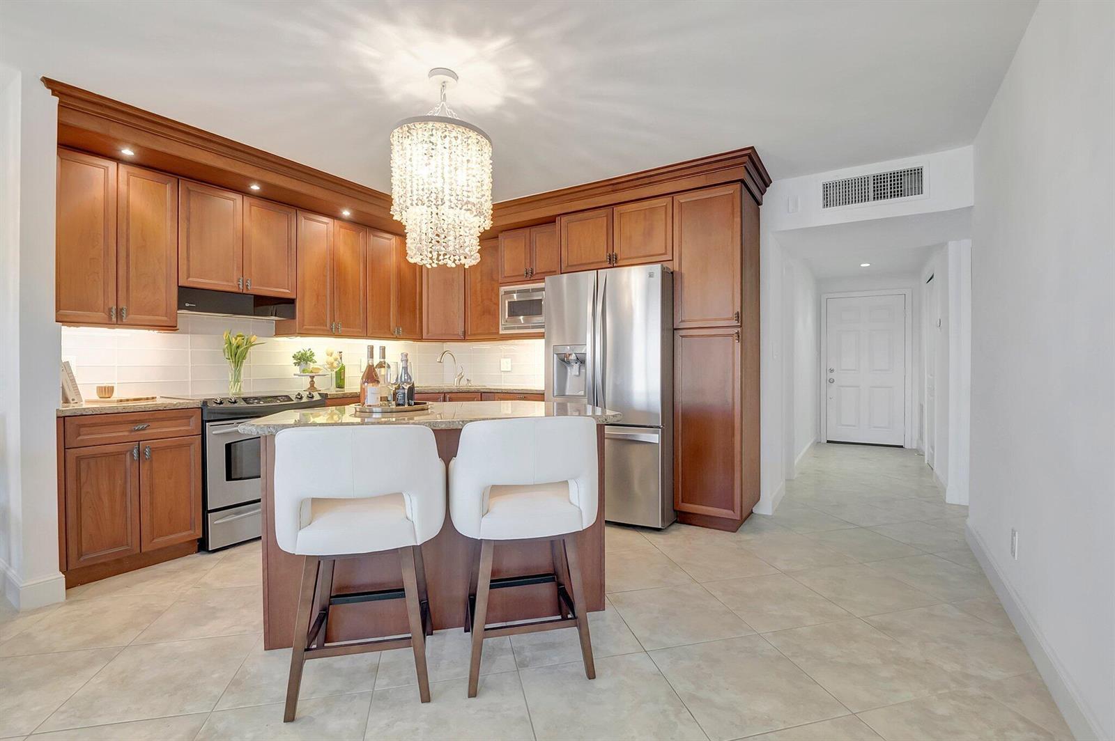 A kitchen with wood cabinets, stainless steel appliances, a crystal chandelier, and a center island — 2871 N Ocean Boulevard # D506, Boca Raton FL 33431, BOCA RATON, FL