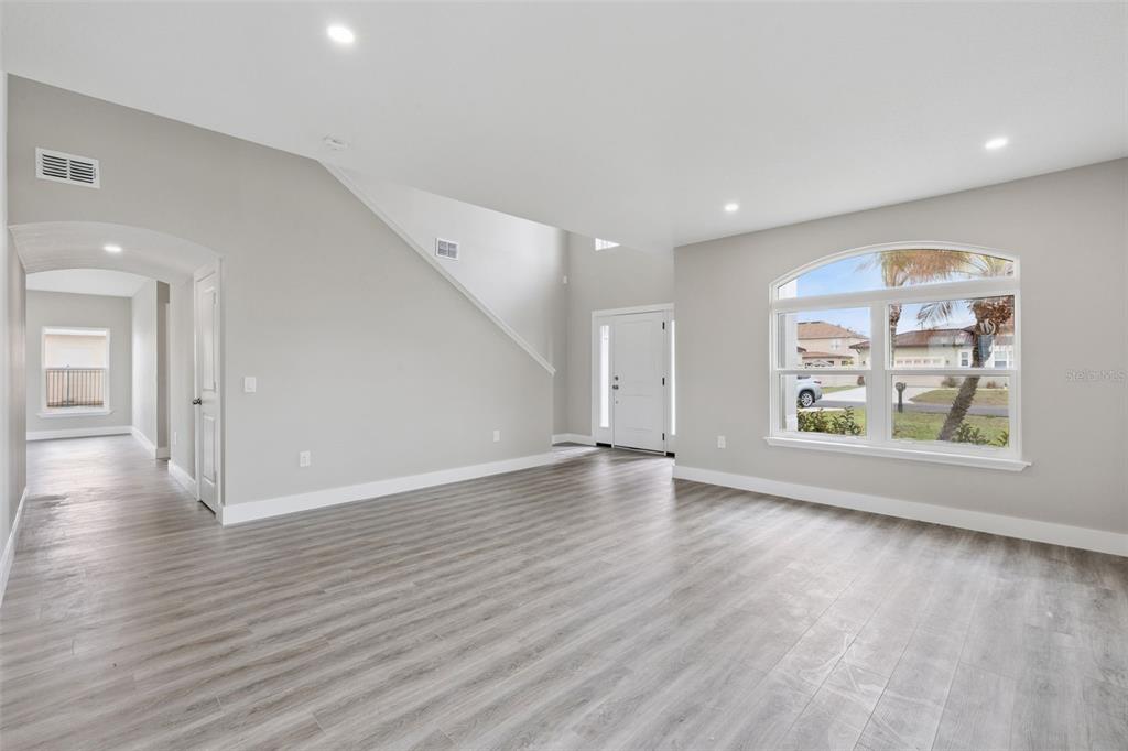 An empty room with light gray walls, wood-look flooring, and a large arched window — 2291 RIO GRANDE CANYON LOOP, KISSIMMEE, FL