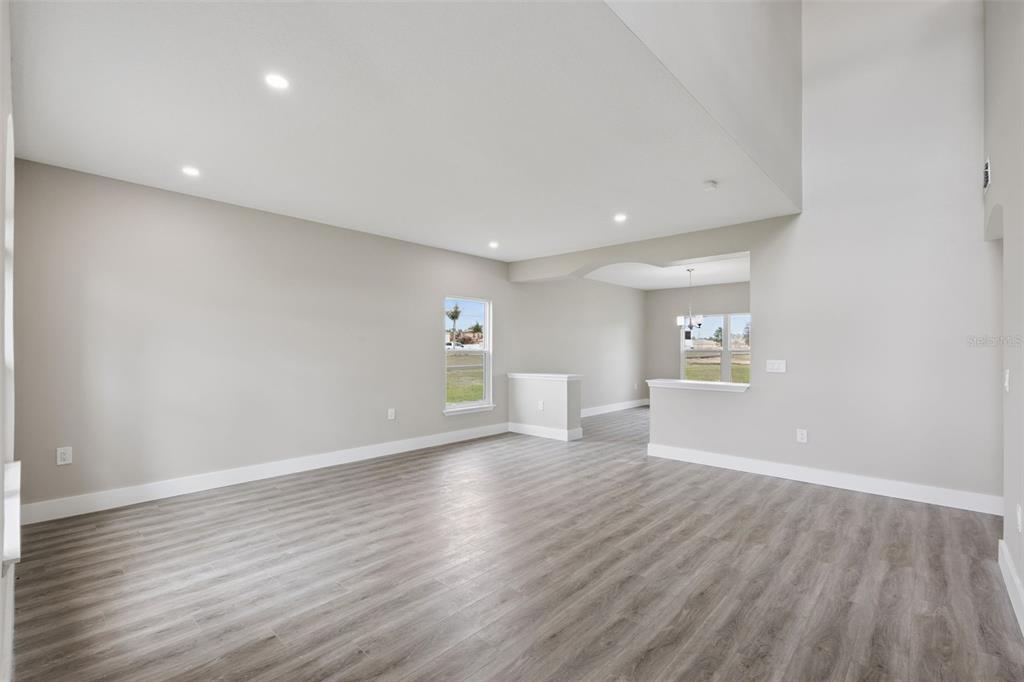 An open-concept living area features light gray walls, wood-look flooring, and a high vaulted ceiling — 2291 RIO GRANDE CANYON LOOP, KISSIMMEE, FL