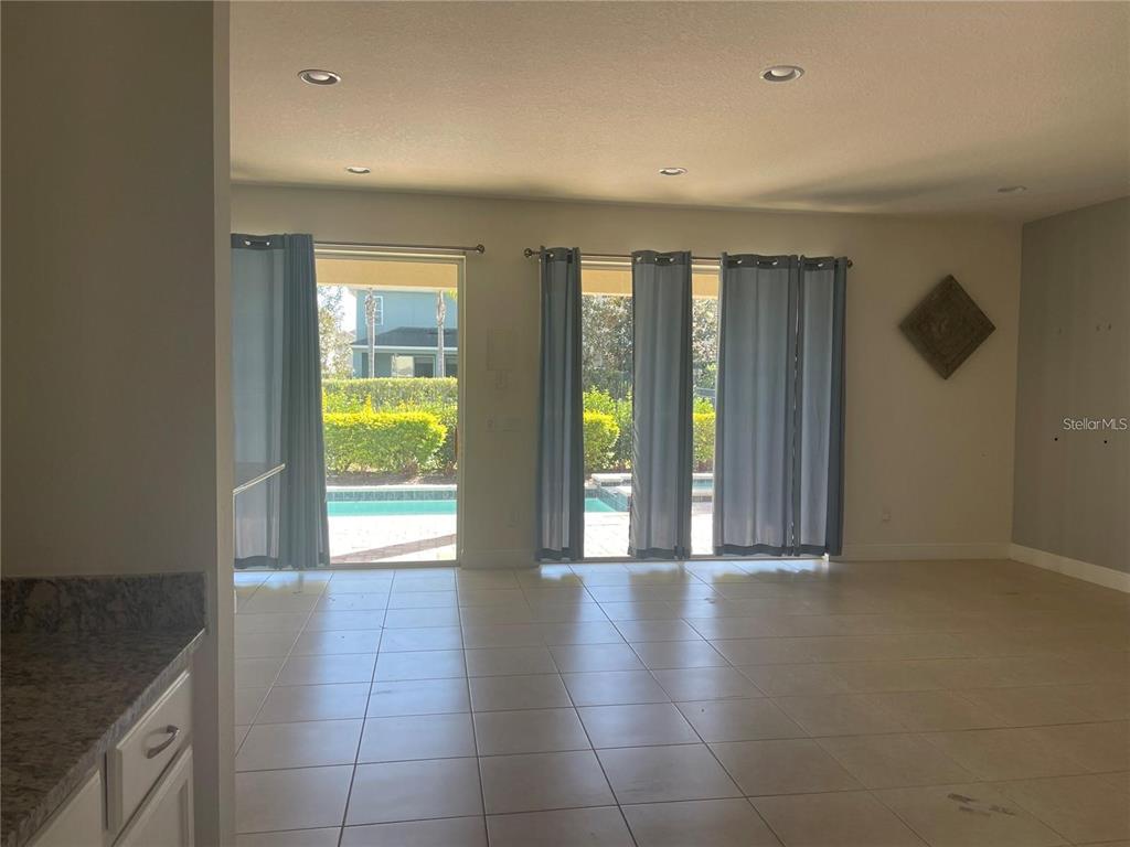A living room with tile flooring, recessed lighting, and sliding glass doors leading to a pool — 210 PENDANT COURT, KISSIMMEE, FL