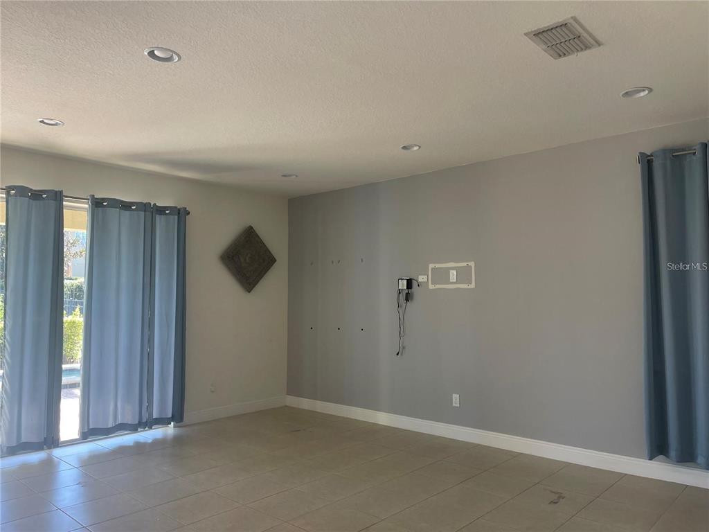 A living room with light tile floors, grey walls, recessed lighting, and blue curtains — 210 PENDANT COURT, KISSIMMEE, FL