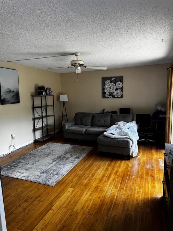 A living room features a gray sectional sofa, a metal shelving unit, and hardwood floors — 1302 NEBRASKA AVENUE UNIT 6A, FORT PIERCE, FL