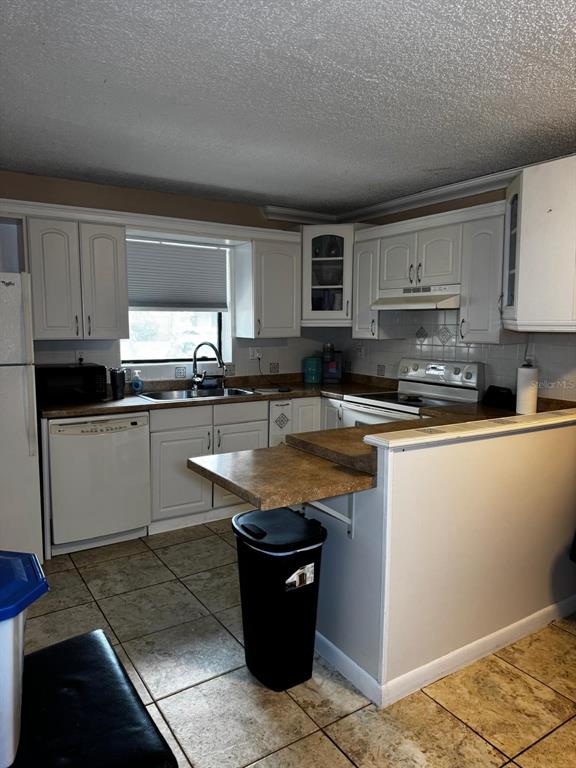 A kitchen features white cabinets, tan laminate countertops, a dishwasher, and tiled flooring — 1302 NEBRASKA AVENUE UNIT 6A, FORT PIERCE, FL