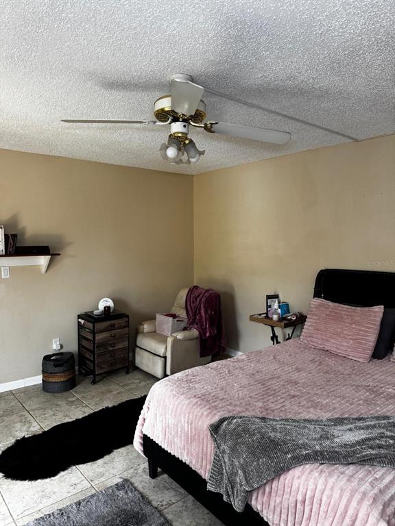 A bedroom features a ceiling fan, a bed with pink bedding, and a recliner chair — 1302 NEBRASKA AVENUE UNIT 6A, FORT PIERCE, FL