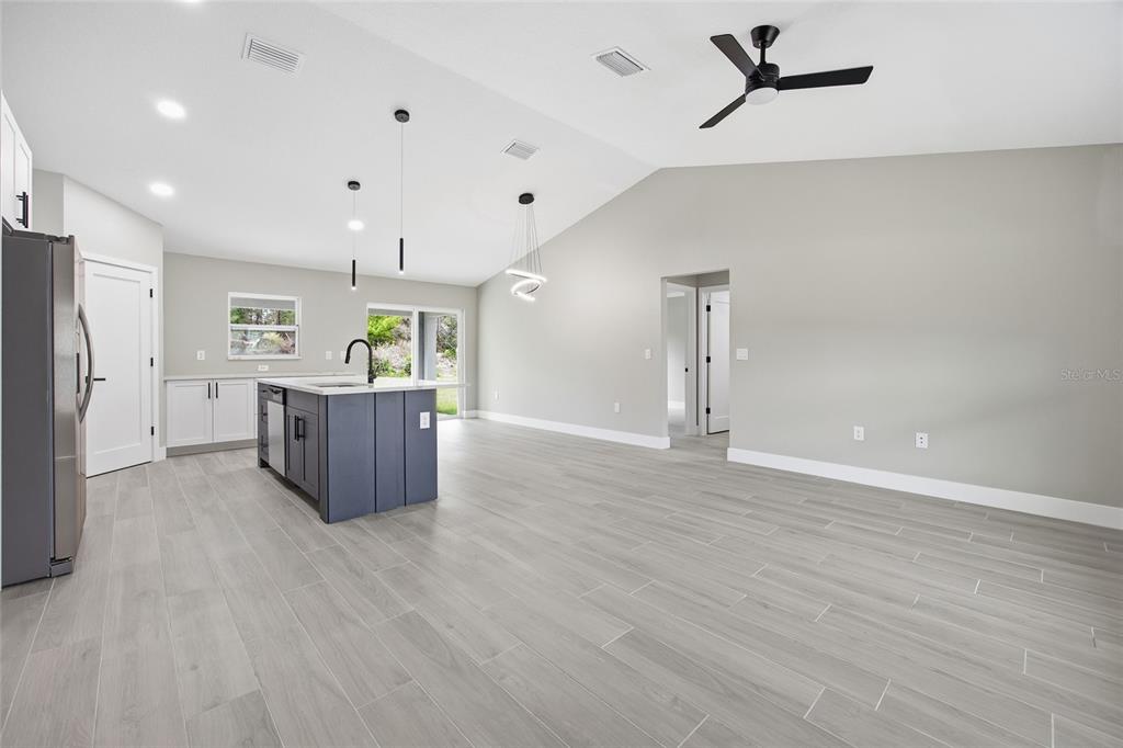 A modern kitchen with a dark blue island and light wood-look tile flooring — 3086 W HAMPSHIRE BOULEVARD, CITRUS SPRINGS, FL