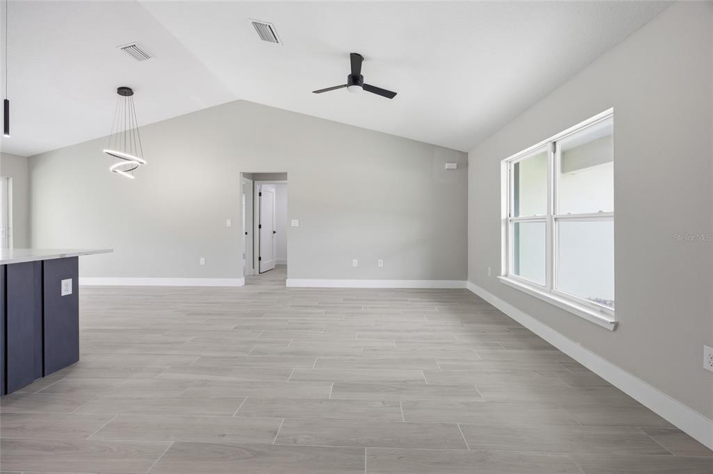 A bright living area features light gray walls, wood-look tile flooring, and a vaulted ceiling — 3086 W HAMPSHIRE BOULEVARD, CITRUS SPRINGS, FL