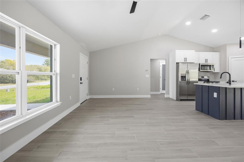 An open-concept living area with light gray walls, wood-look tile flooring, and a kitchen island — 3086 W HAMPSHIRE BOULEVARD, CITRUS SPRINGS, FL