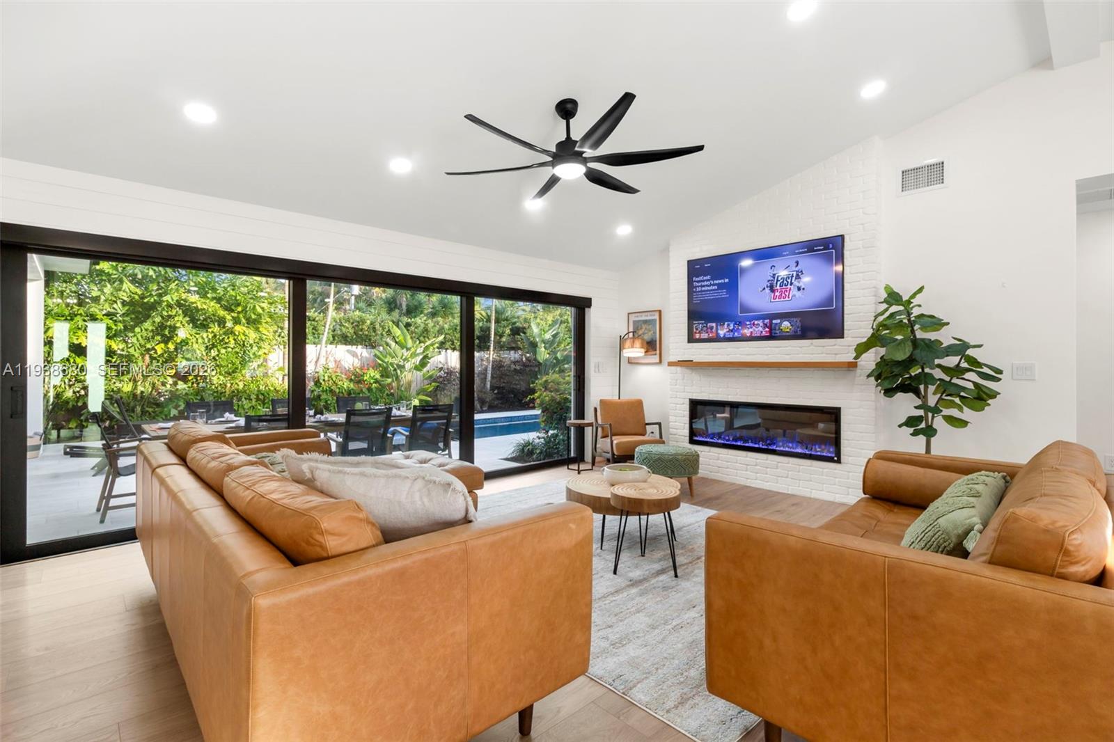 A living room features two leather sofas, a white brick fireplace, and large sliding glass doors — 3540 NE 28th Ave, Lighthouse Point FL 33064, LIGHTHOUSE POINT, FL