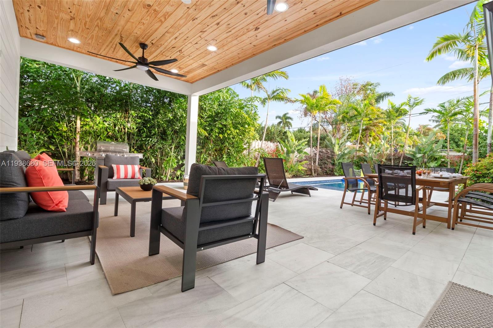 A covered patio features a wood-paneled ceiling, outdoor furniture, and a view of a pool — 3540 NE 28th Ave, Lighthouse Point FL 33064, LIGHTHOUSE POINT, FL