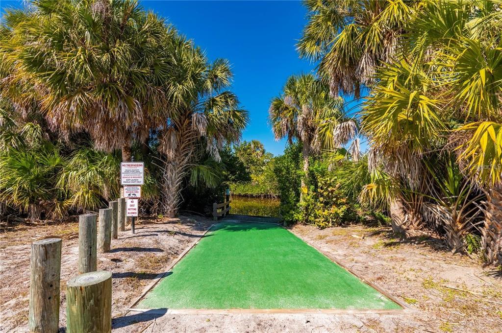 A green launch ramp leads to a waterway surrounded by palm trees and wooden posts — 16490 TRADING POST ROAD, PUNTA GORDA, FL