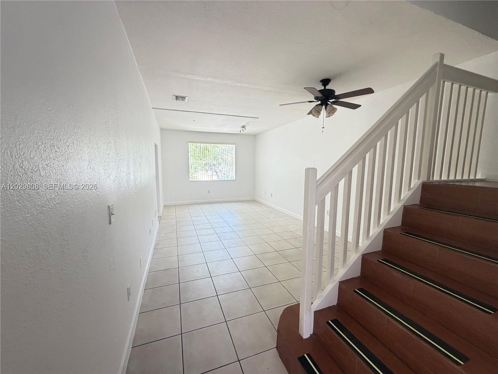 A living room features white walls, tile flooring, a ceiling fan, and a wooden staircase — 7080 NW 177th St # 13, Hialeah FL 33015, HIALEAH, FL