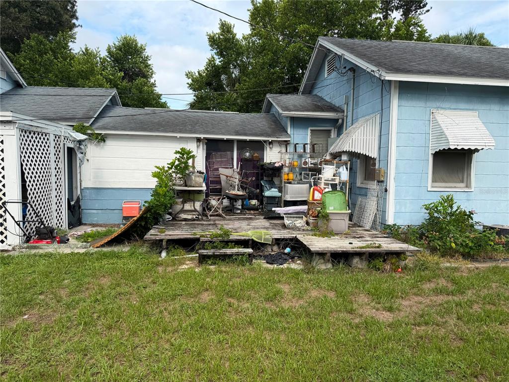 A weathered wooden deck sits behind a light blue house with a cluttered patio area — 4227 2ND AVENUE S, ST PETERSBURG, FL