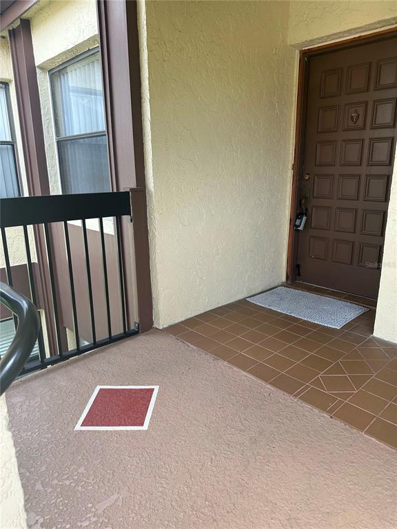 An exterior entryway features a brown paneled door, tiled flooring, and a black metal railing — 3245 CANDLE RIDGE DRIVE UNIT 203, ORLANDO, FL