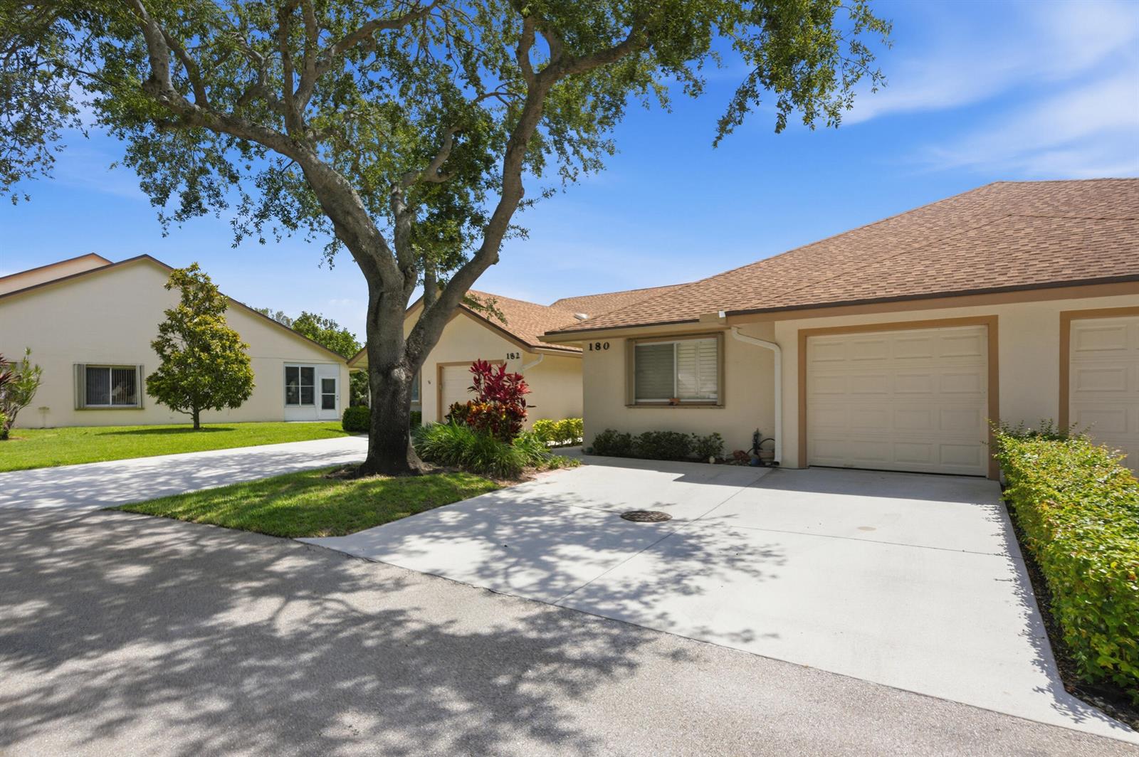 A view of two single-story residential buildings with attached garages and concrete driveways — 180 Par Drive, Royal Palm Beach FL 33411, ROYAL PALM BEACH, FL