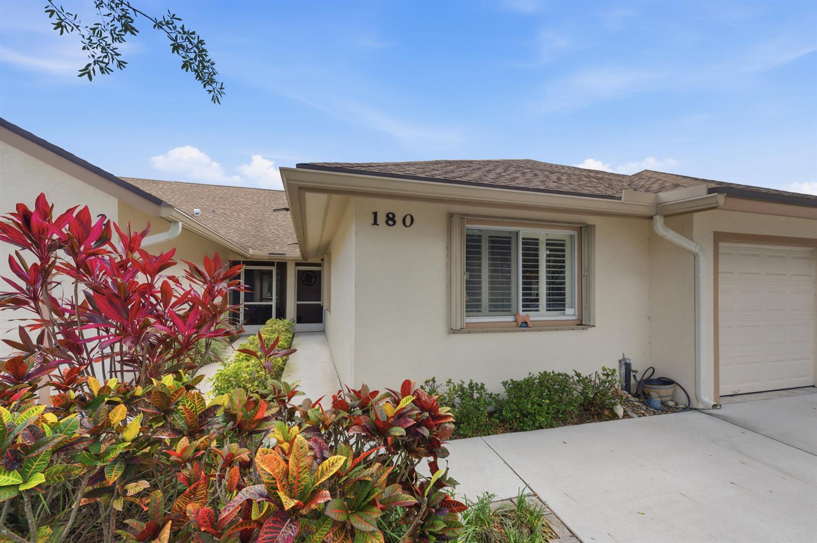 A single-story beige house with a garage, a front walkway, and colorful landscaping — 180 Par Drive, Royal Palm Beach FL 33411, ROYAL PALM BEACH, FL