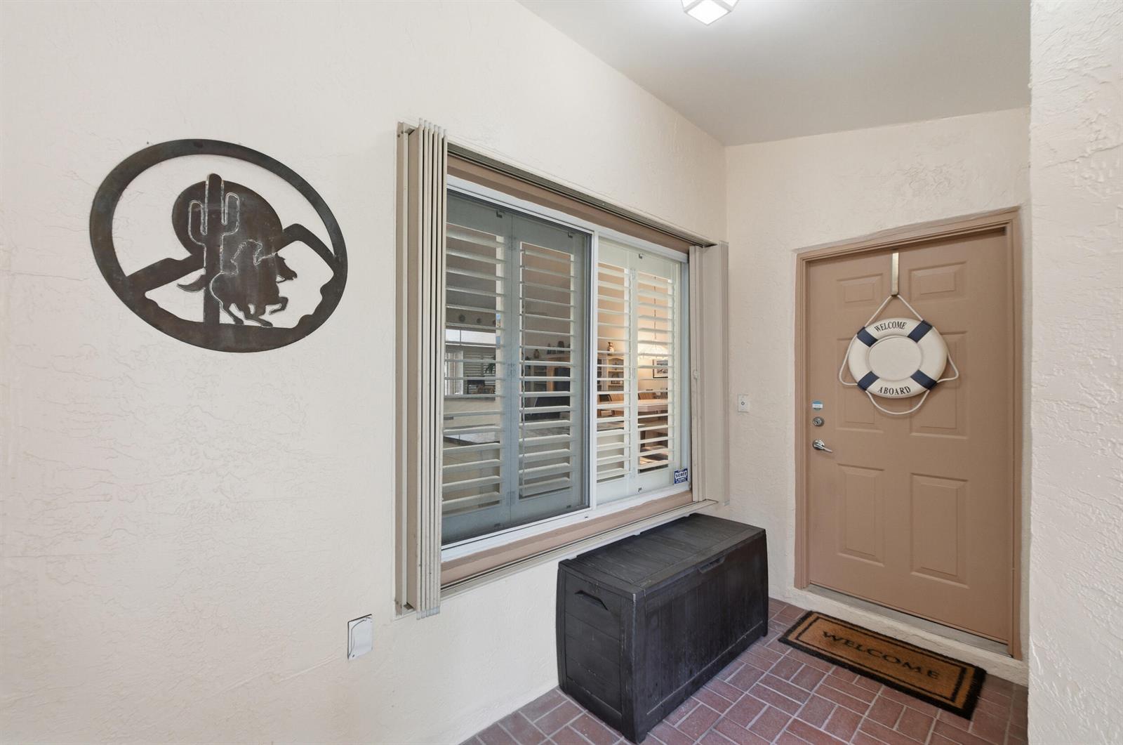 A covered entryway features a tan door, a window with shutters, and a storage bench — 180 Par Drive, Royal Palm Beach FL 33411, ROYAL PALM BEACH, FL