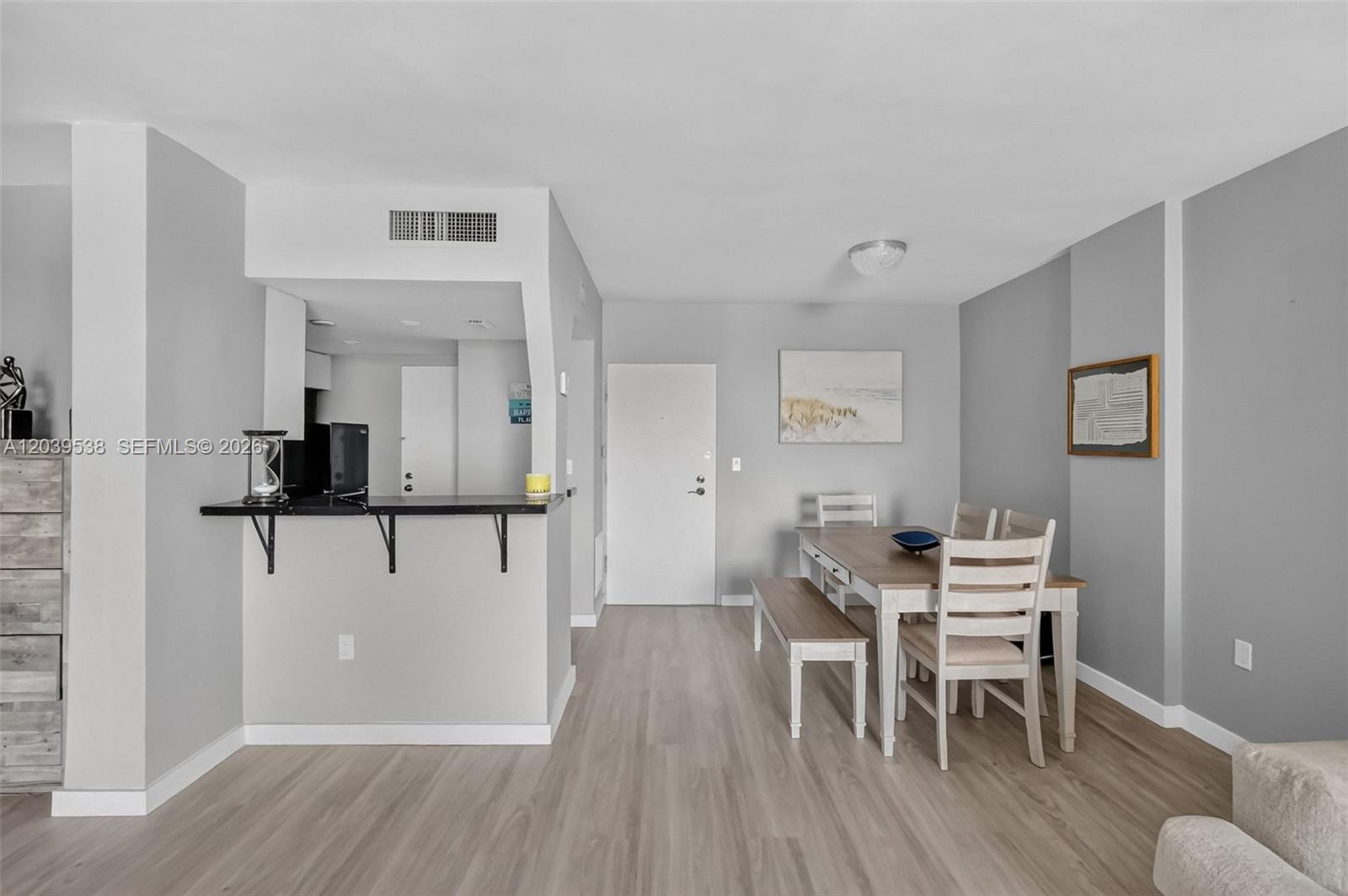 A dining area with a wooden table and bench sits next to a kitchen counter — 800 West Ave # 533, Miami Beach FL 33139, MIAMI BEACH, FL