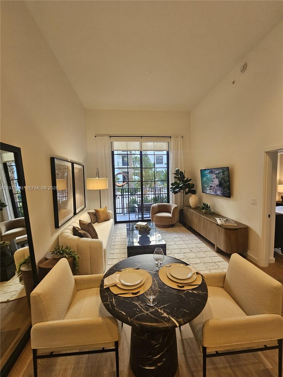 A living and dining area features high ceilings, a marble table, and a balcony view — 1650 NE 124th St # 102, North Miami FL 33181, NORTH MIAMI, FL