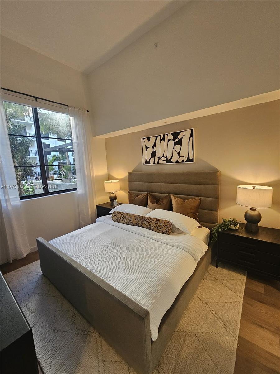 A bedroom features a gray upholstered bed, two nightstands with lamps, and a window with curtains — 1650 NE 124th St # 102, North Miami FL 33181, NORTH MIAMI, FL