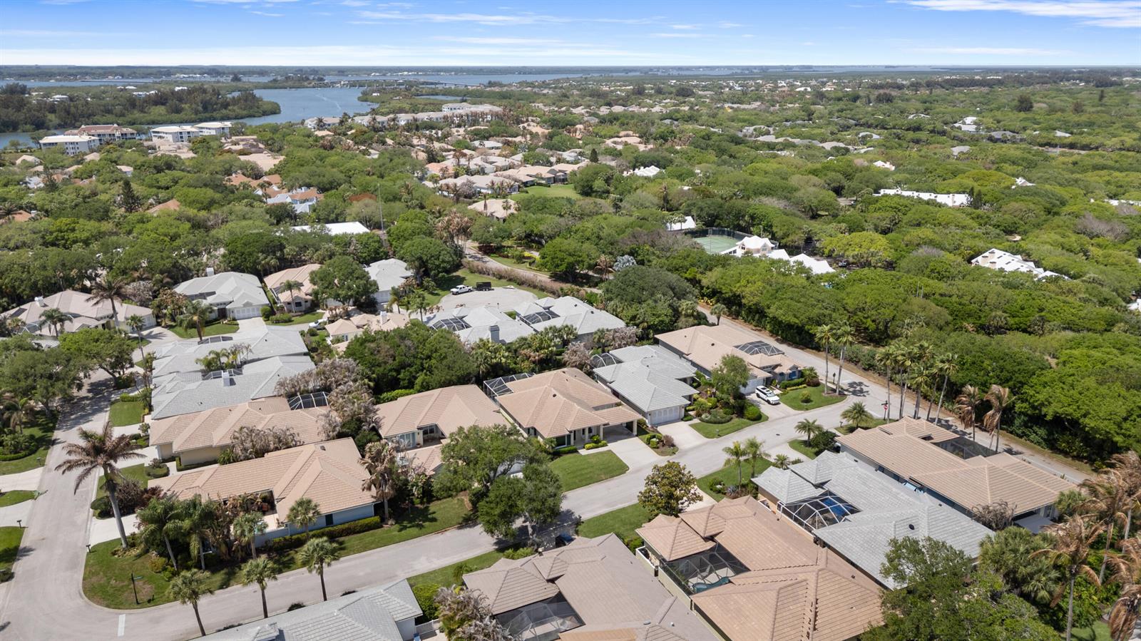 An aerial view shows a residential neighborhood with houses featuring tan roofs and swimming pools — VERO BEACH, FL
