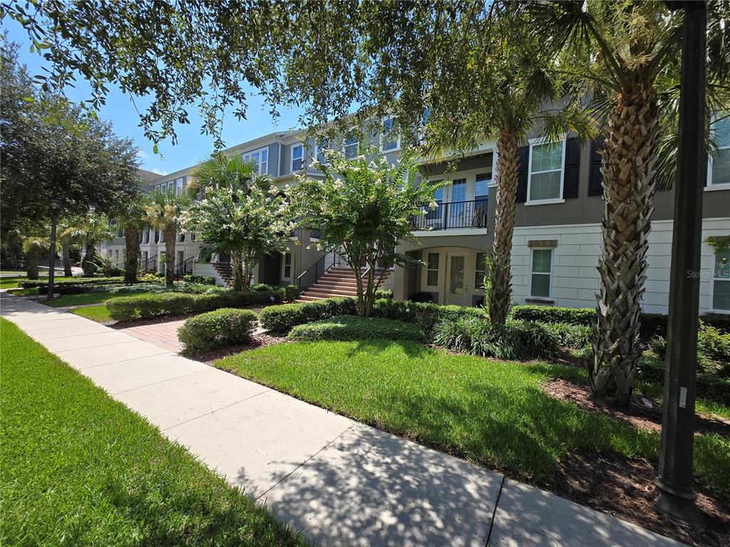 A multi-story apartment building exterior features a sidewalk, manicured lawn, and palm trees — 529 LANARK COURT, ORLANDO, FL