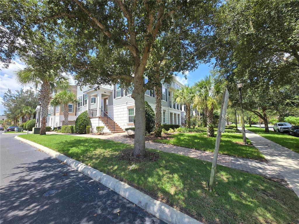 A multi-story residential building with light-colored siding and brick accents sits behind a grassy lawn — 529 LANARK COURT, ORLANDO, FL