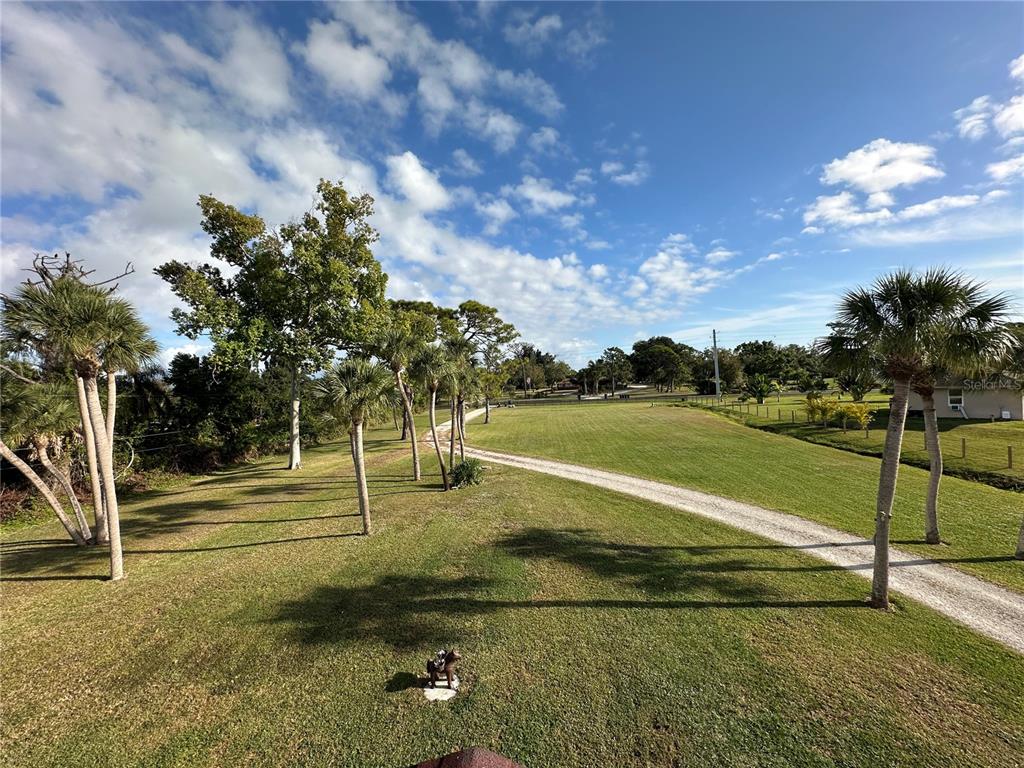 A single-story house with light siding and red trim stands behind a grassy yard — 1181 LARCHMONT DRIVE, ENGLEWOOD, FL