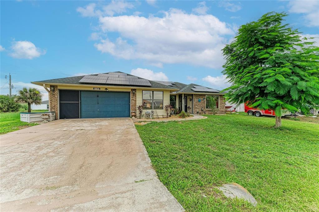 A single-story house with a blue garage door, solar panels, and a large front lawn — 2147 FLORIBANNA STREET, NORTH PORT, FL