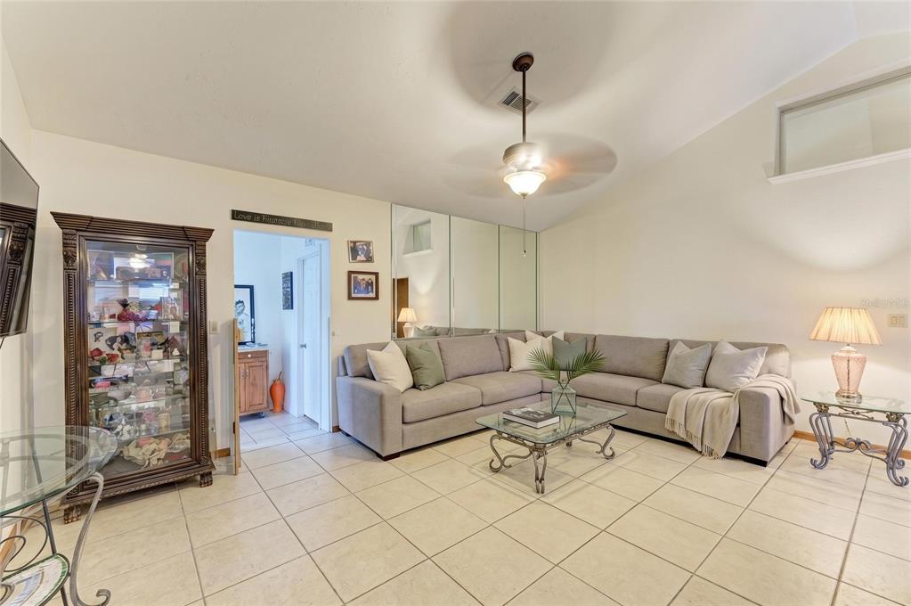 A living room features a grey sectional sofa, mirrored wall panels, and tile flooring — 2147 FLORIBANNA STREET, NORTH PORT, FL