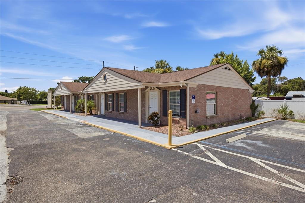 A single-story brick commercial building with a covered walkway and an adjacent asphalt parking lot — 4911 STATE ROAD 54, NEW PORT RICHEY, FL
