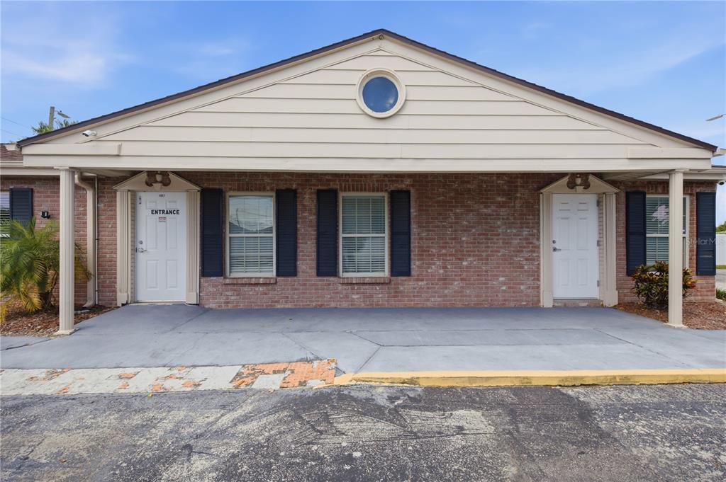 A brick commercial building exterior features two white entrance doors under a covered walkway — 4911 STATE ROAD 54, NEW PORT RICHEY, FL