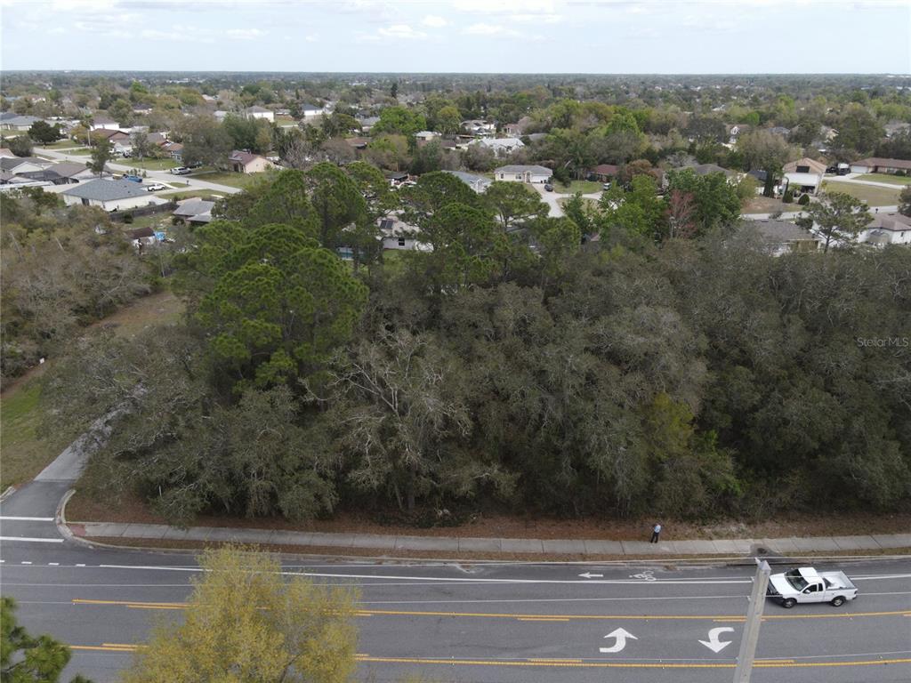 An aerial view shows a wooded vacant lot bordered by a road and residential houses — 752 FORT SMITH BOULEVARD, DELTONA, FL