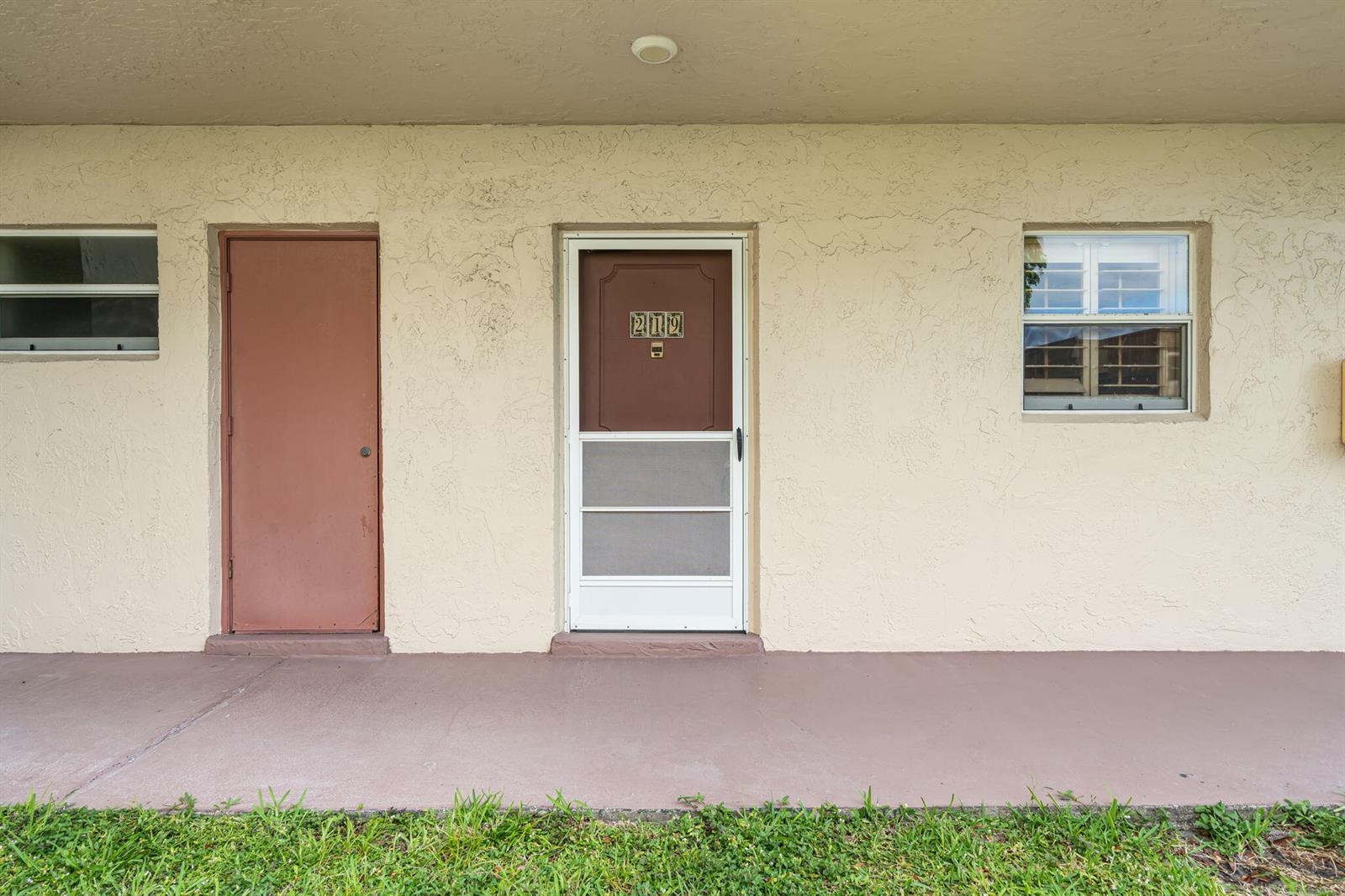 An exterior view of a building featuring a door labeled 212, a side door, and windows — 752 Lori Drive # 219, Palm Springs FL 33461, PALM SPRINGS, FL