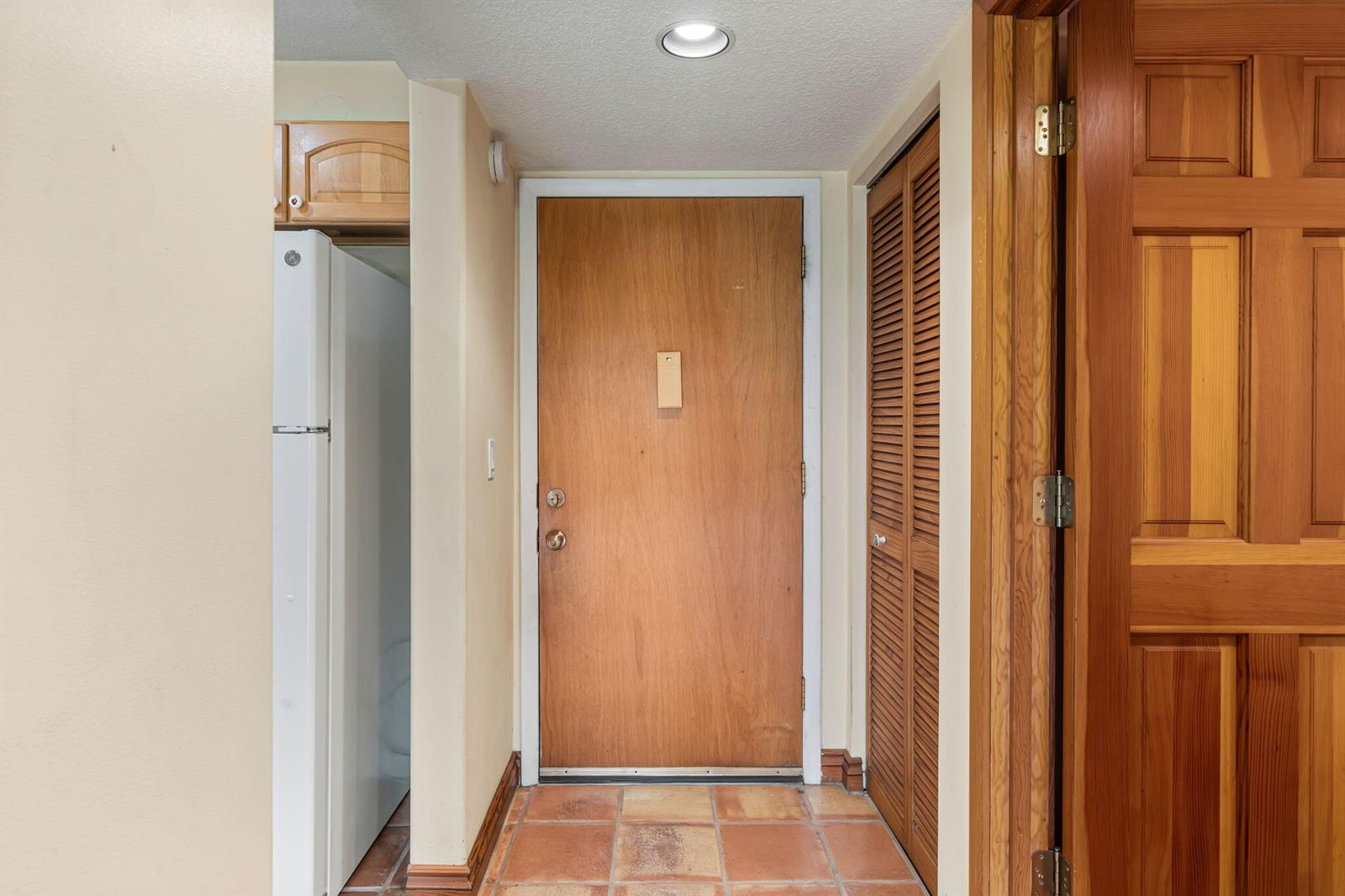 An entryway features a wooden door, terracotta tile flooring, and a louvered closet door — 752 Lori Drive # 219, Palm Springs FL 33461, PALM SPRINGS, FL