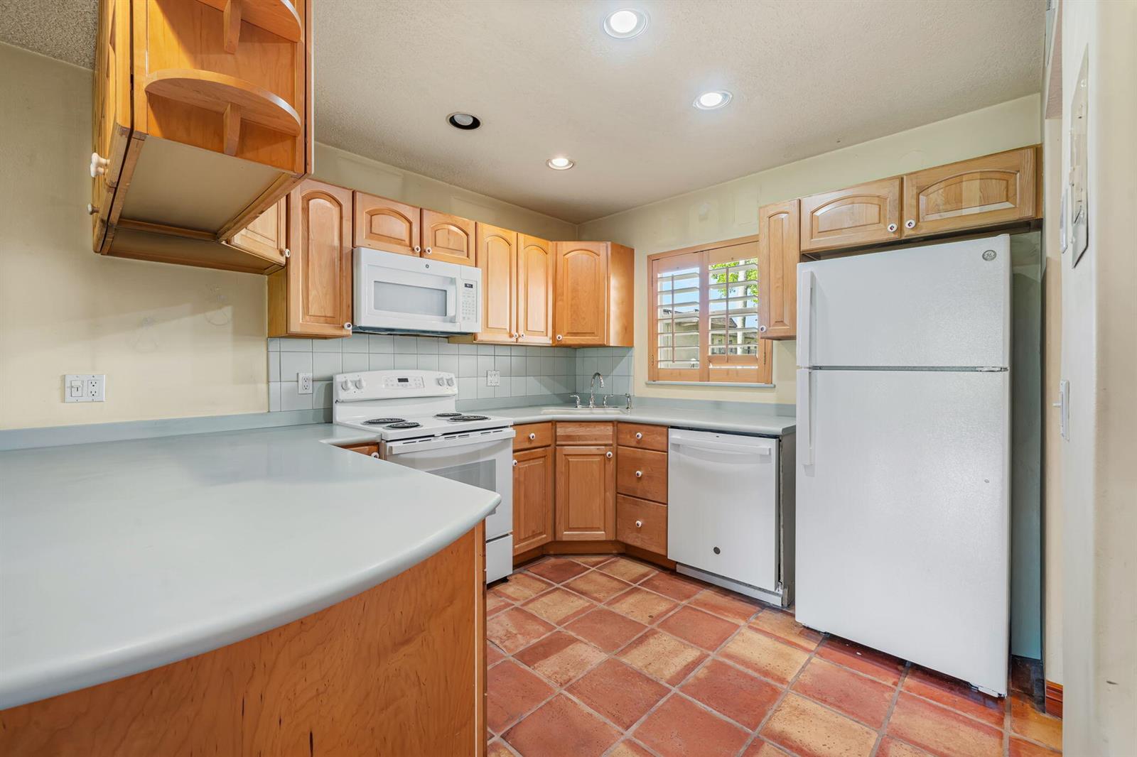A kitchen features wood cabinets, white appliances, a light countertop, and terracotta tile flooring — 752 Lori Drive # 219, Palm Springs FL 33461, PALM SPRINGS, FL