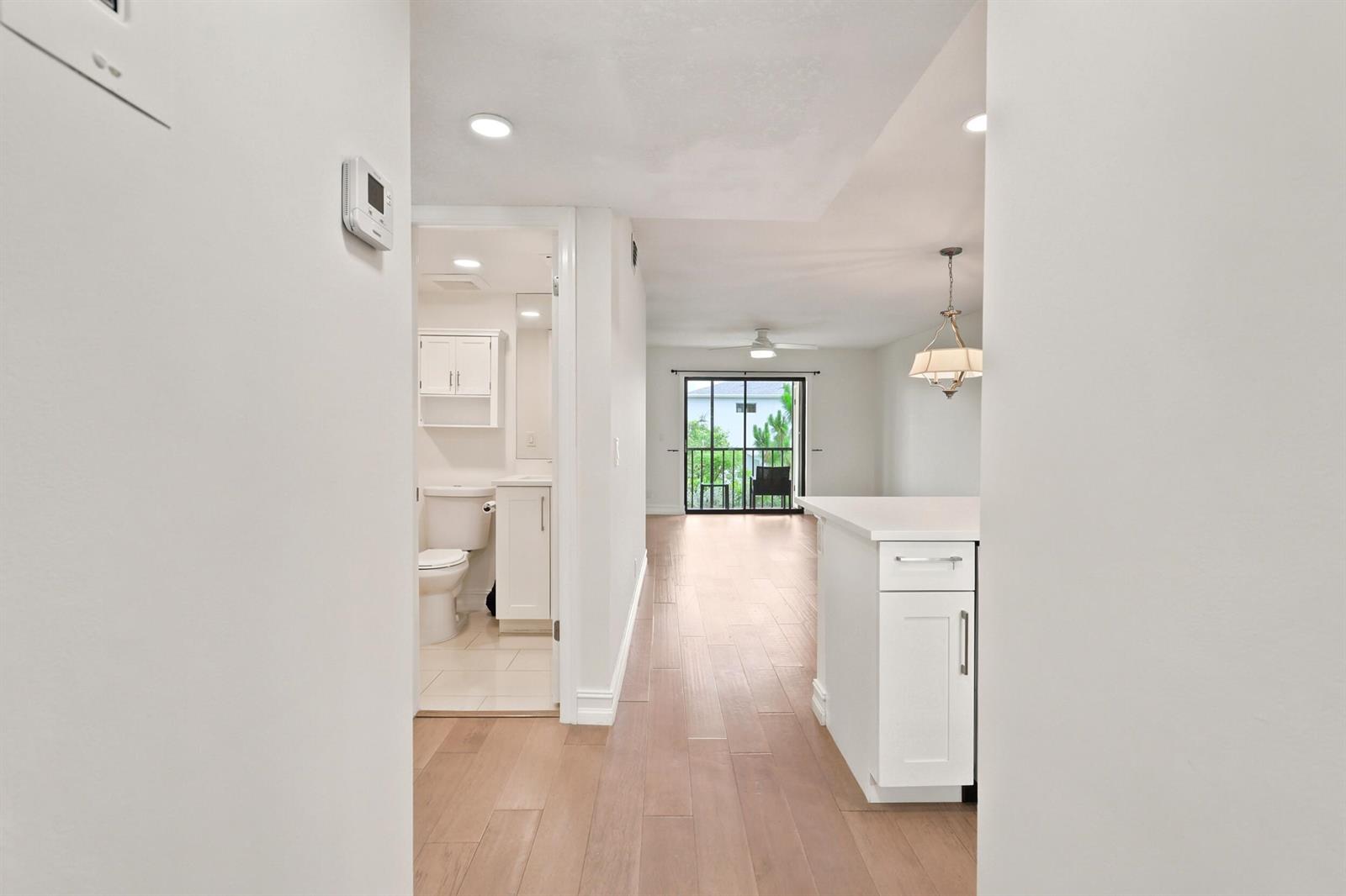 A hallway leads past a bathroom and kitchen toward a living area with a balcony — 7209 Golf Colony Court # 203, Lake Worth FL 33467, LAKE WORTH, FL