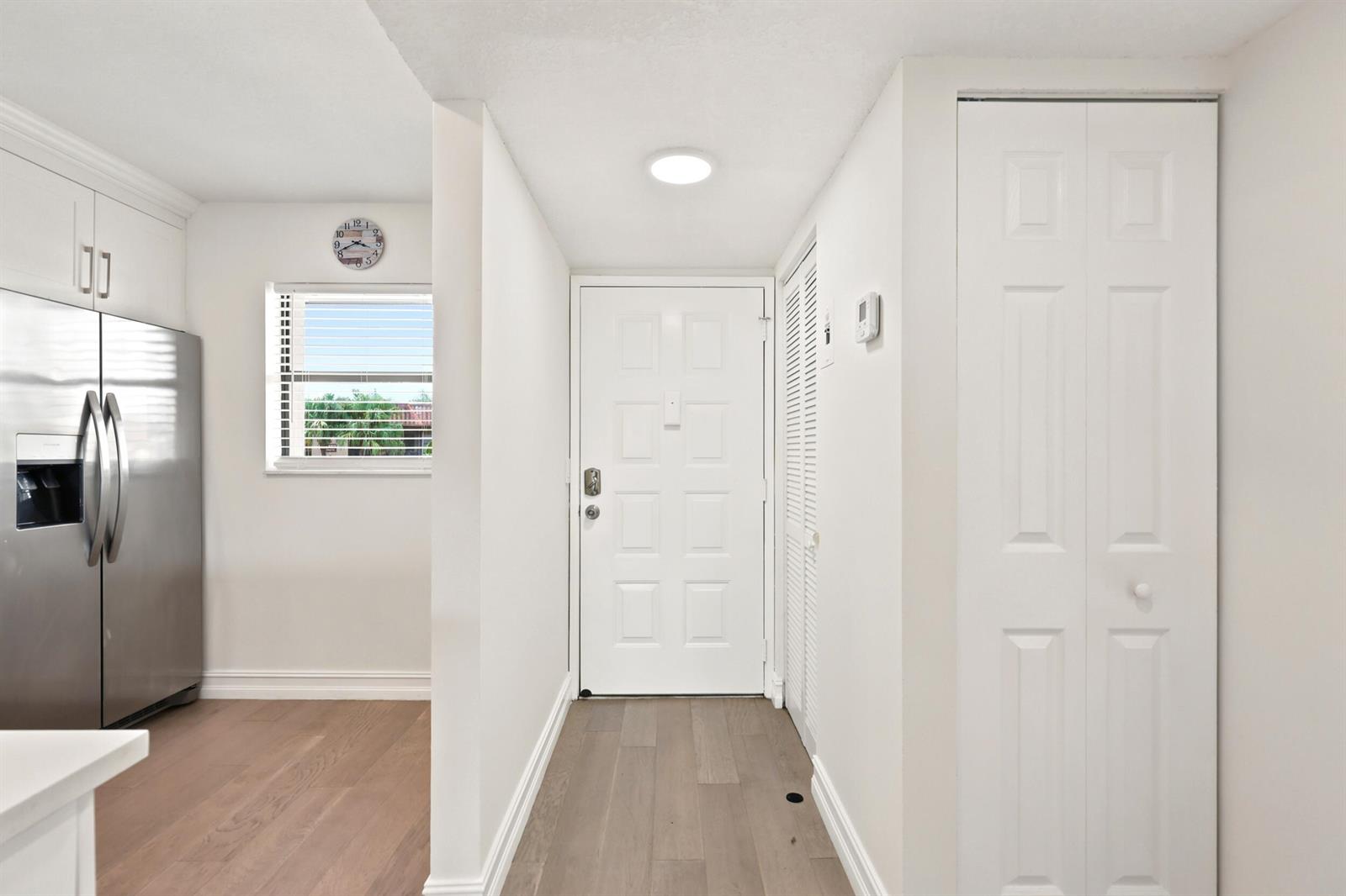 A white entryway features a front door, a closet, and a view into a kitchen — 7209 Golf Colony Court # 203, Lake Worth FL 33467, LAKE WORTH, FL