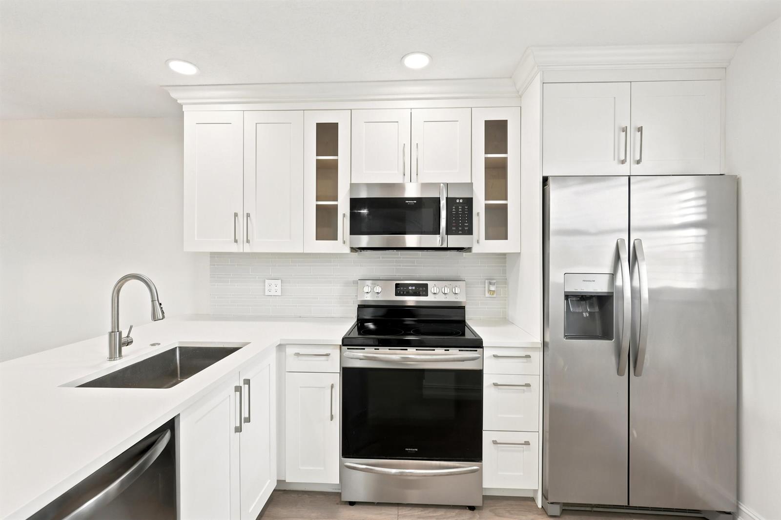 A kitchen with white cabinets, stainless steel appliances, a sink, and white countertops — 7209 Golf Colony Court # 203, Lake Worth FL 33467, LAKE WORTH, FL