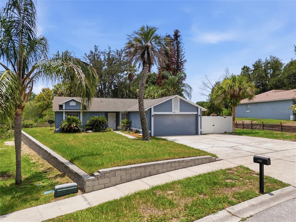A single-story blue house with a two-car garage and a front yard with palm trees — 10641 LAKE RALPH DRIVE, CLERMONT, FL