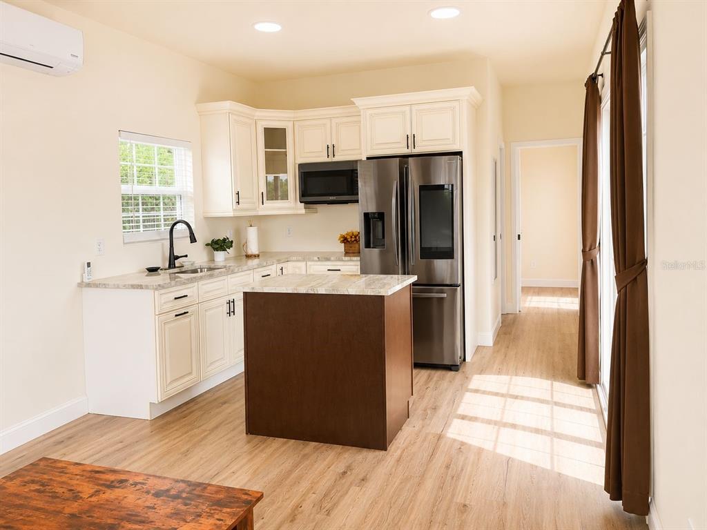 A kitchen features white cabinets, a dark wood island, stainless steel appliances, and light flooring — 9459 SE 47TH WAY, WEBSTER, FL