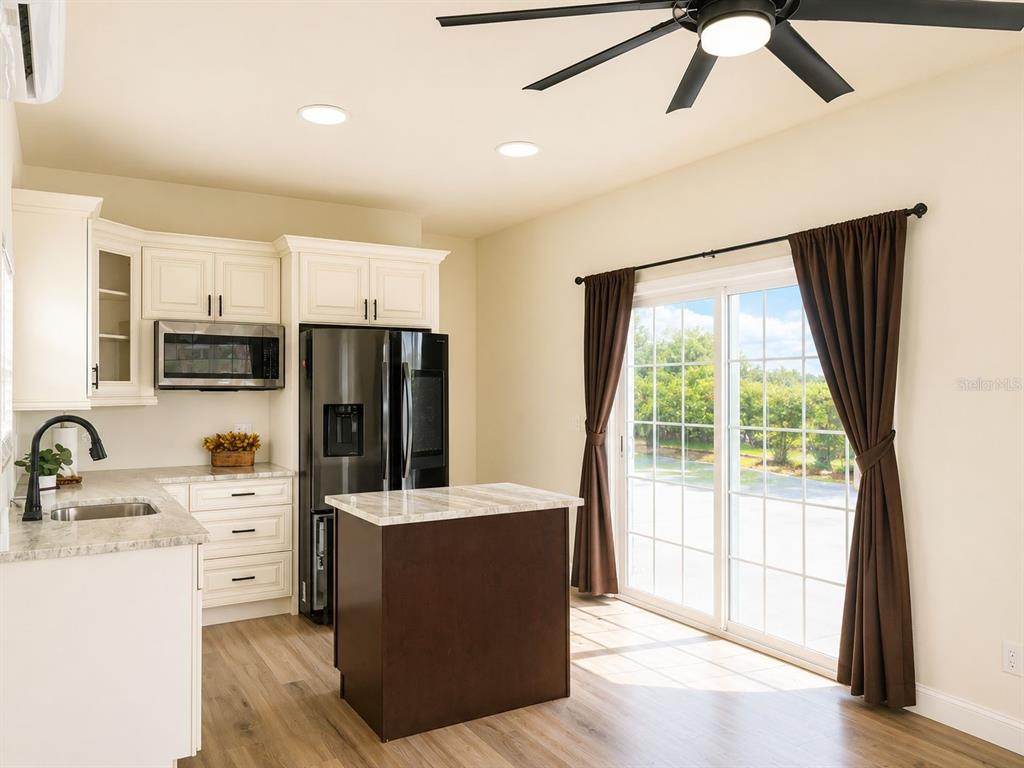 A kitchen with white cabinets, a dark island, stainless appliances, and sliding glass doors — 9459 SE 47TH WAY, WEBSTER, FL
