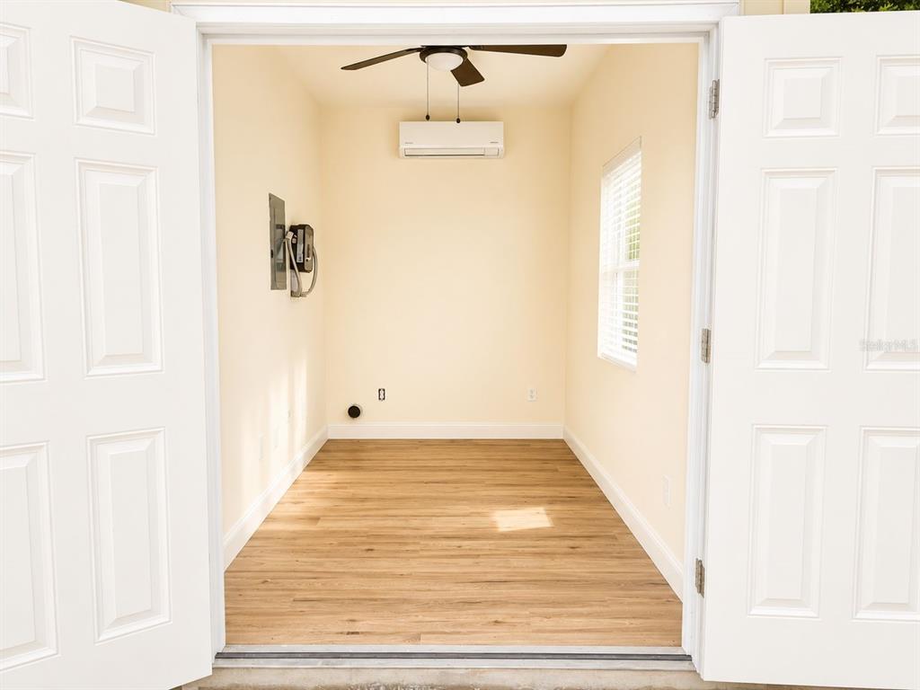 A small, empty room features light-colored walls, wood-look flooring, a ceiling fan, and a wall-mounted air conditioner — 9459 SE 47TH WAY, WEBSTER, FL